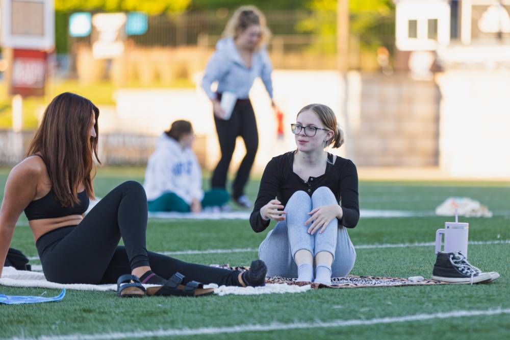 Two students sitting on the Football Field during a yoga session at sunset